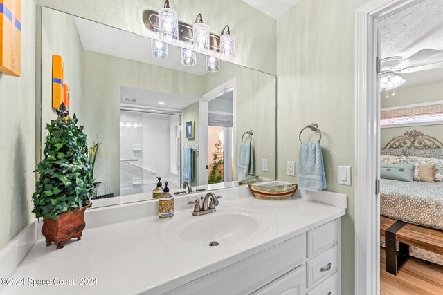 bathroom featuring hardwood / wood-style floors, ceiling fan, a textured ceiling, and vanity