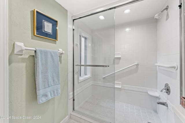 bathroom featuring a tile shower and a textured wall