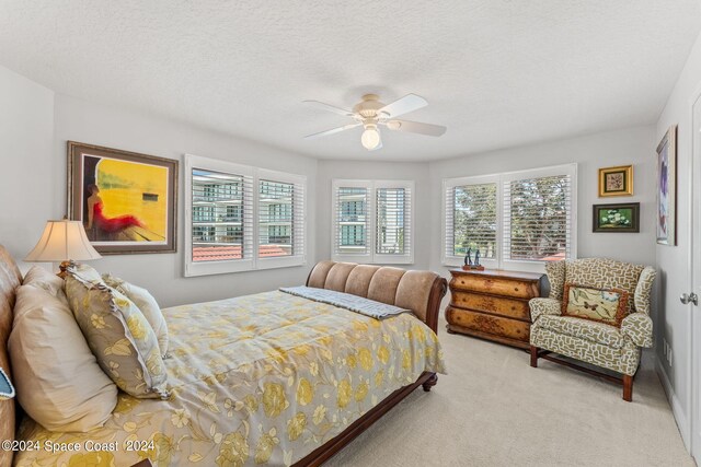 carpeted bedroom featuring multiple windows, ceiling fan, and a textured ceiling