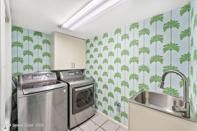 clothes washing area featuring a sink, baseboards, cabinet space, washer and clothes dryer, and wallpapered walls