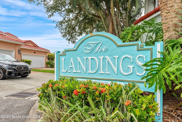 community sign featuring concrete driveway and an attached garage