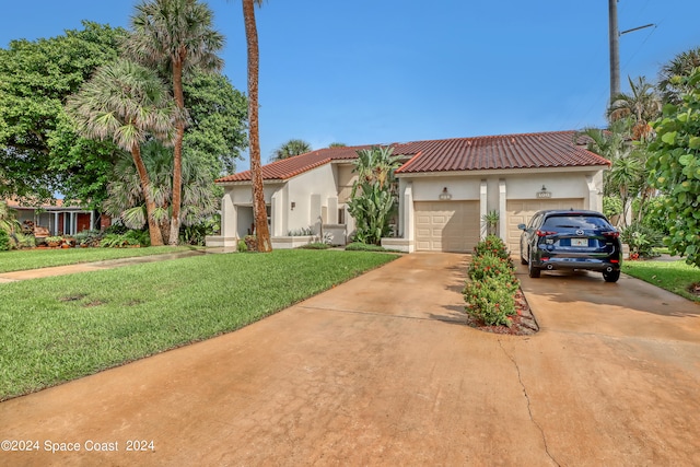 mediterranean / spanish-style home featuring a garage and a front lawn