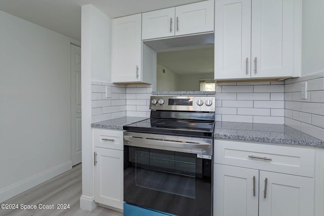 kitchen with electric range, decorative backsplash, white cabinetry, and light hardwood / wood-style flooring