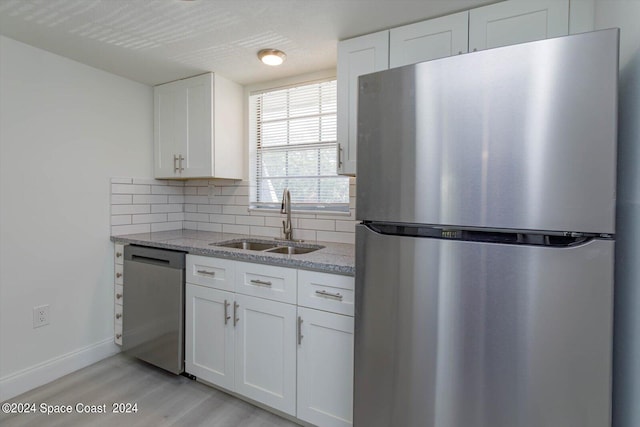 250 Berkshire Ln, Melbourne, FL 32935 - kitchen featuring light wood-style flooring, a sink, white cabinets, appliances with stainless steel finishes, and decorative backsplash