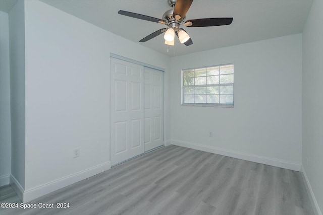 unfurnished bedroom featuring ceiling fan, a closet, and light wood-type flooring