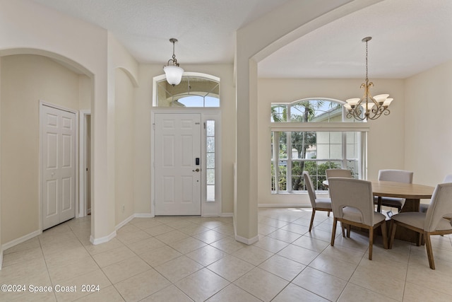 foyer entrance featuring light tile patterned floors, a wealth of natural light, and a notable chandelier