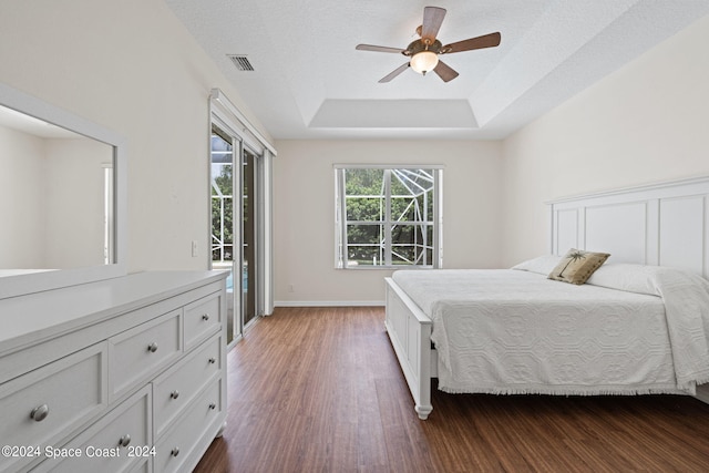 bedroom with a raised ceiling, access to exterior, ceiling fan, and dark hardwood / wood-style floors