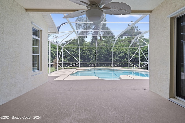 view of swimming pool with ceiling fan, a patio area, and glass enclosure