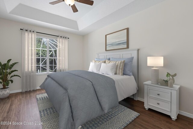 bedroom with dark wood-type flooring, ceiling fan, and a tray ceiling