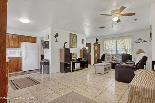 living room featuring ceiling fan, light tile patterned floors, and a textured ceiling