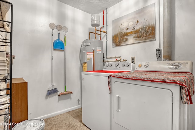 laundry room featuring light wood-type flooring, water heater, a textured ceiling, and washer and dryer