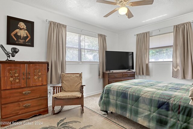 carpeted bedroom with a textured ceiling, ceiling fan, and multiple windows