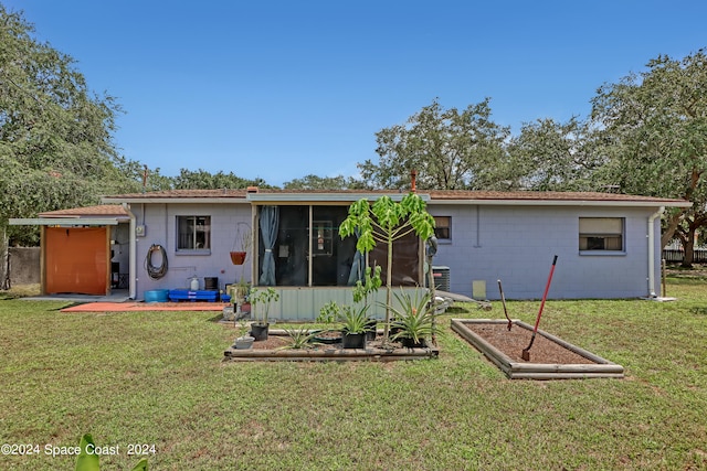 back of property with a yard and a sunroom