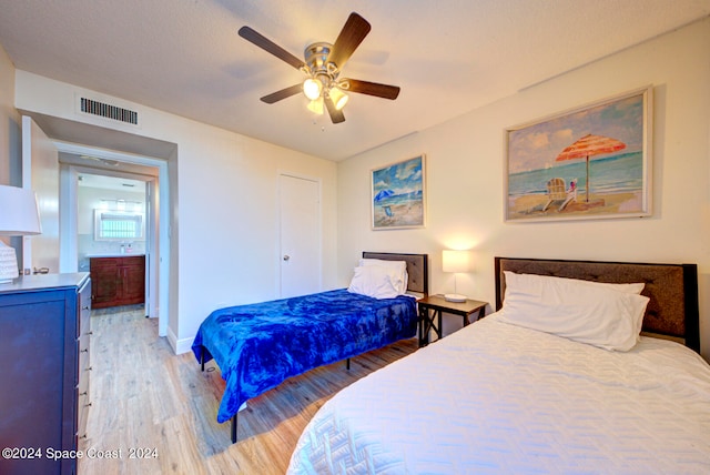 bedroom with hardwood / wood-style flooring, connected bathroom, and ceiling fan