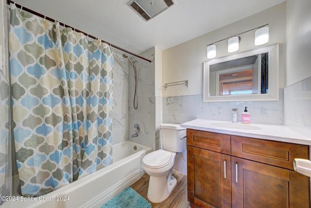 full bathroom featuring toilet, hardwood / wood-style floors, vanity, shower / bath combo, and tile walls