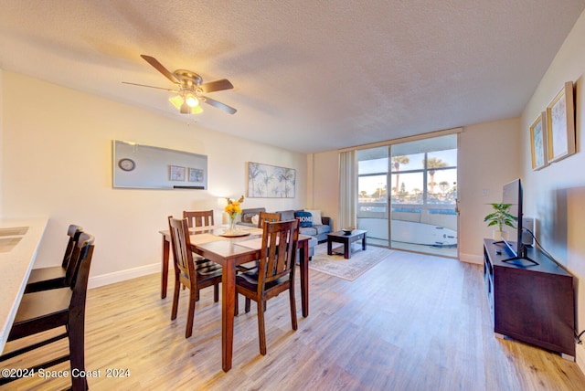 dining area with a textured ceiling, light hardwood / wood-style flooring, ceiling fan, and expansive windows