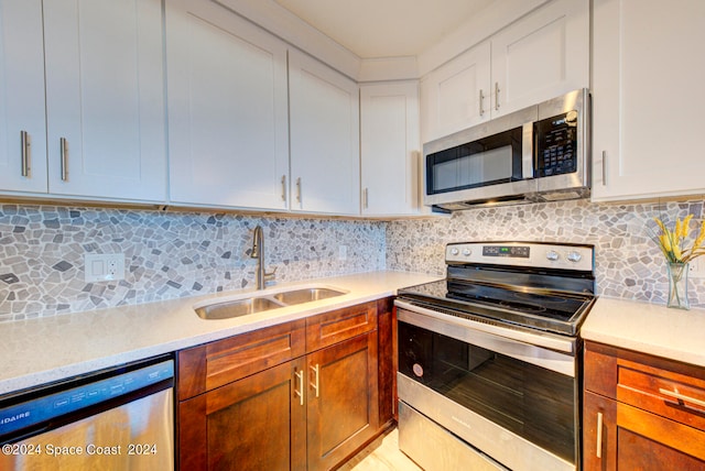 kitchen featuring appliances with stainless steel finishes, white cabinetry, sink, and decorative backsplash