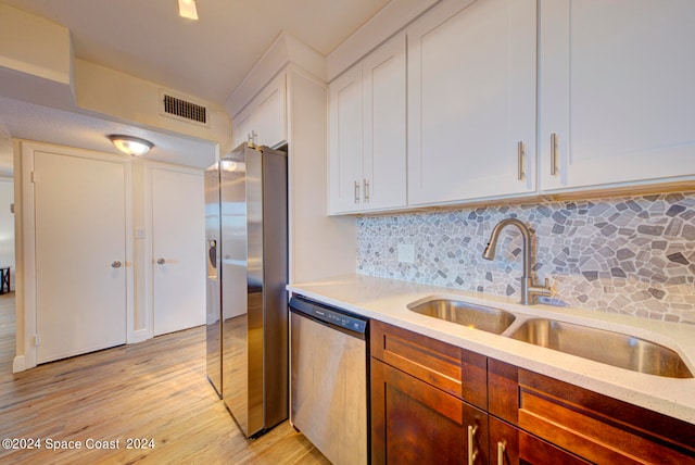 kitchen featuring light hardwood / wood-style flooring, appliances with stainless steel finishes, tasteful backsplash, sink, and white cabinetry