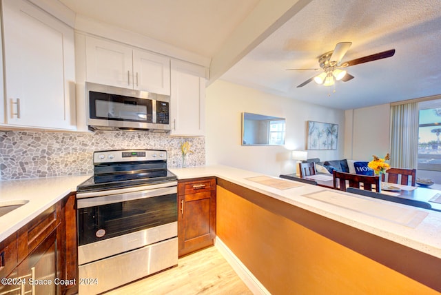 kitchen featuring light hardwood / wood-style flooring, backsplash, appliances with stainless steel finishes, ceiling fan, and white cabinets