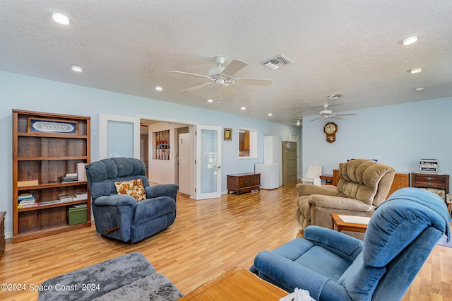 living room with light wood-type flooring, a textured ceiling, and ceiling fan