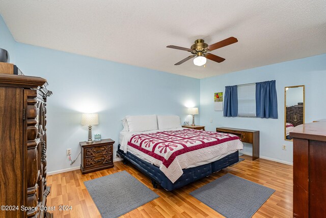 bedroom with light wood-type flooring, a textured ceiling, and ceiling fan