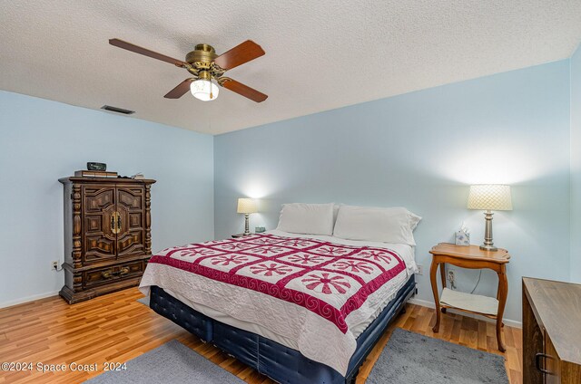 bedroom featuring light wood-type flooring, a textured ceiling, and ceiling fan