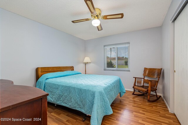 bedroom with ceiling fan, hardwood / wood-style flooring, and a textured ceiling