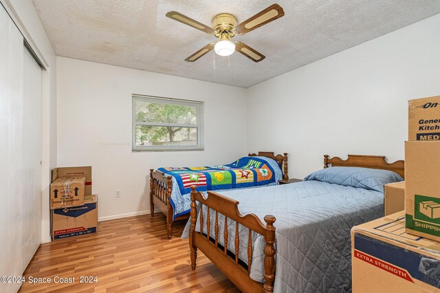 bedroom with a textured ceiling, ceiling fan, a closet, and light wood-type flooring