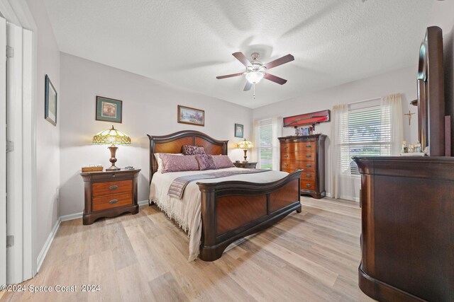 bedroom featuring light wood-type flooring, ceiling fan, and a textured ceiling