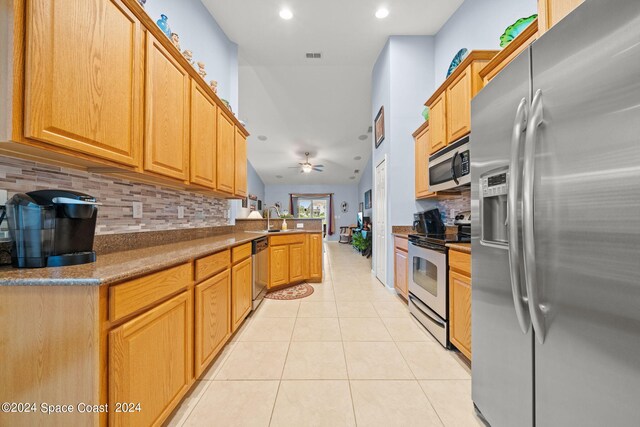 kitchen featuring backsplash, light tile patterned floors, stainless steel appliances, sink, and ceiling fan