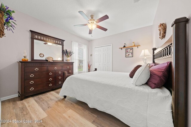 bedroom featuring a textured ceiling, ceiling fan, a closet, and light hardwood / wood-style floors