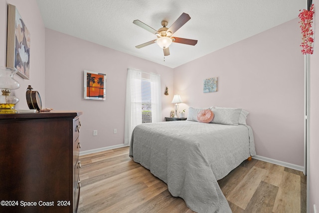 bedroom with light wood-type flooring, a textured ceiling, and ceiling fan