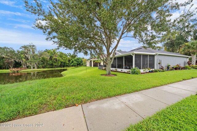 view of yard with a sunroom and a water view