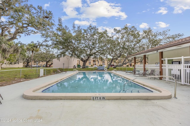 community pool with a patio and fence