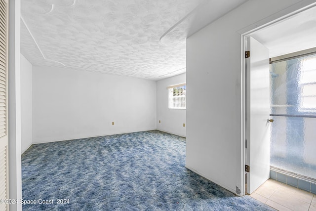 unfurnished room featuring a textured ceiling and carpet flooring