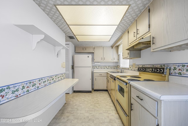 kitchen featuring white appliances, visible vents, light countertops, under cabinet range hood, and a sink