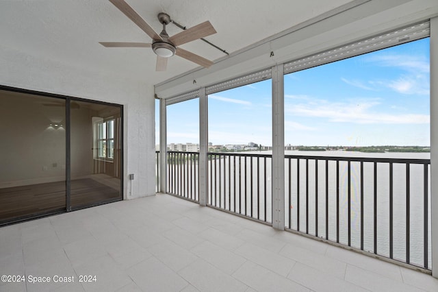 unfurnished sunroom with ceiling fan and a water view