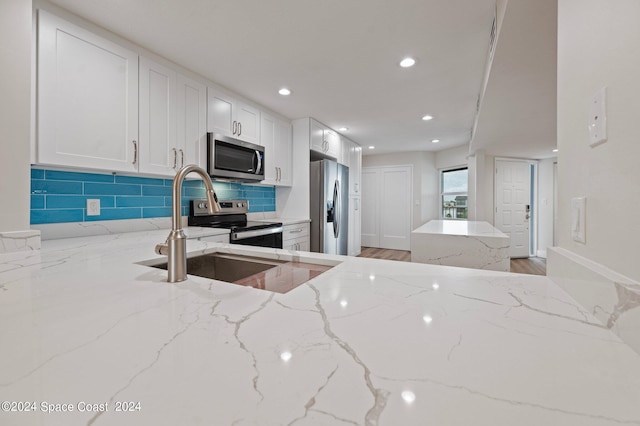 kitchen with light wood-type flooring, appliances with stainless steel finishes, backsplash, and white cabinetry