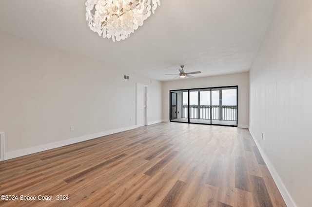 spare room with light wood-type flooring and ceiling fan with notable chandelier