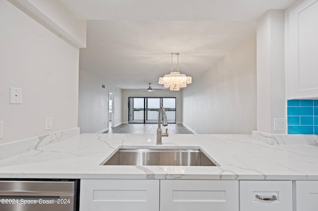 kitchen with ceiling fan with notable chandelier, light stone countertops, sink, and stainless steel dishwasher