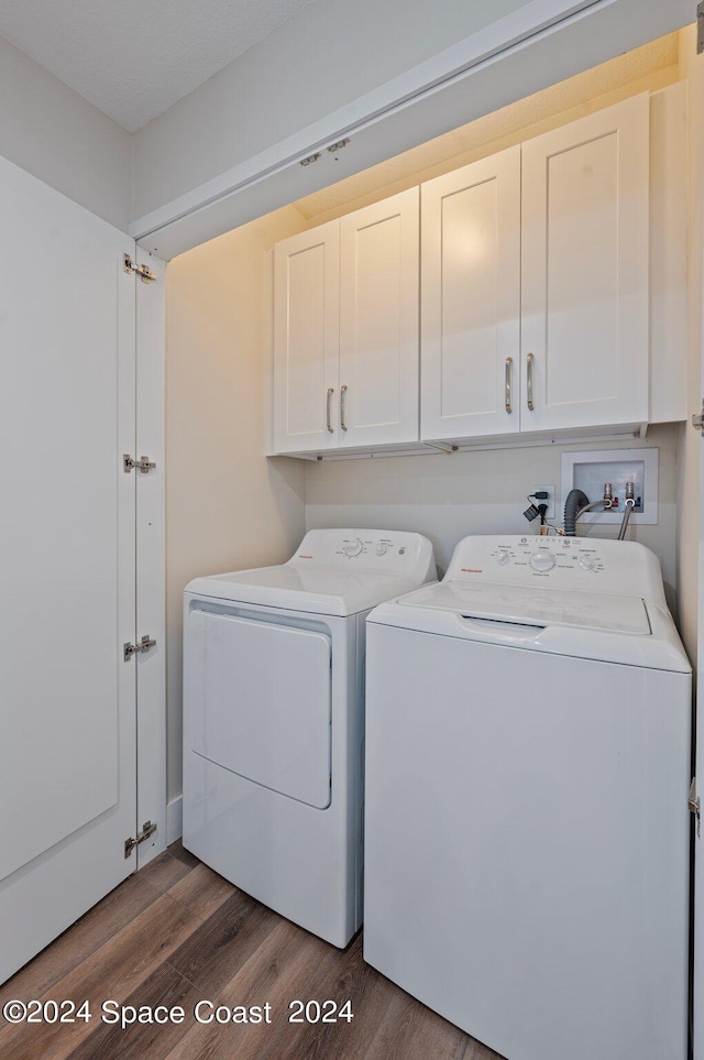 washroom featuring dark wood-type flooring, cabinets, and washer and dryer