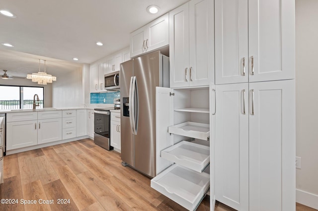 kitchen featuring decorative light fixtures, white cabinets, stainless steel appliances, and light hardwood / wood-style floors