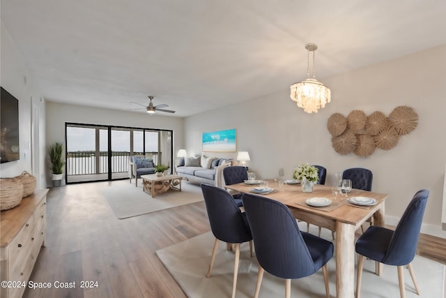 dining room with ceiling fan with notable chandelier and light hardwood / wood-style flooring