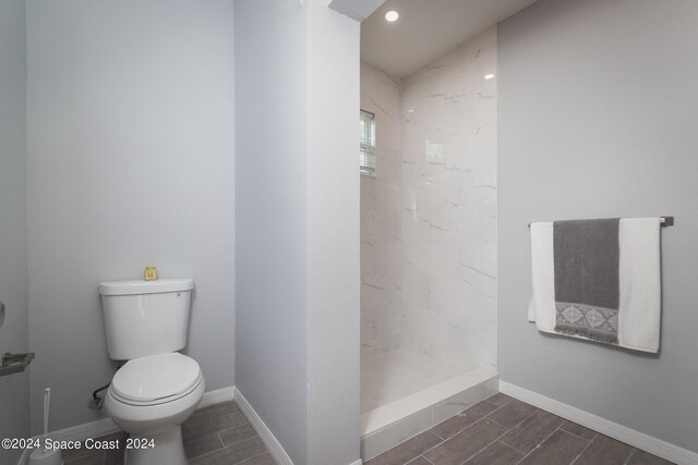 bathroom featuring toilet and a tile shower