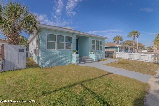 bungalow-style house with a front yard, brick siding, and fence