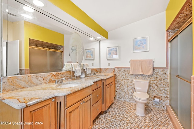 bathroom featuring vanity, a shower with shower door, tile walls, toilet, and tile patterned floors