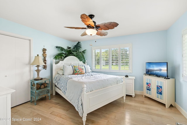 bedroom with light hardwood / wood-style flooring, ceiling fan, and a closet