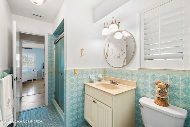 bathroom with an enclosed shower, tile walls, toilet, and vanity