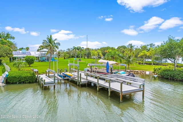 view of dock with a lawn and a water view