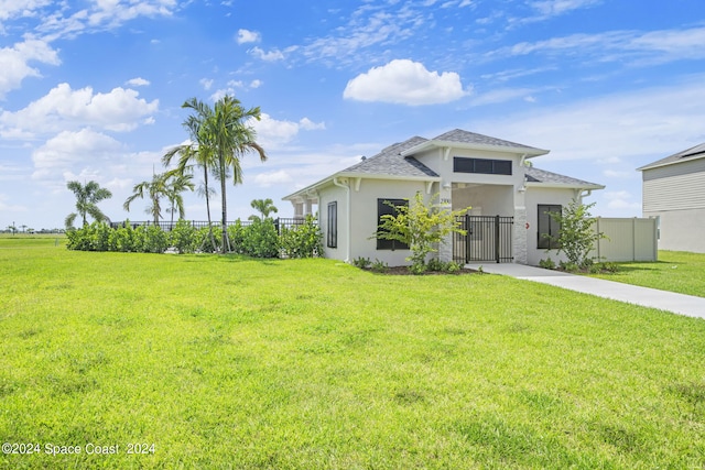 view of front facade with a front lawn, a shingled roof, a fenced front yard, a gate, and stucco siding